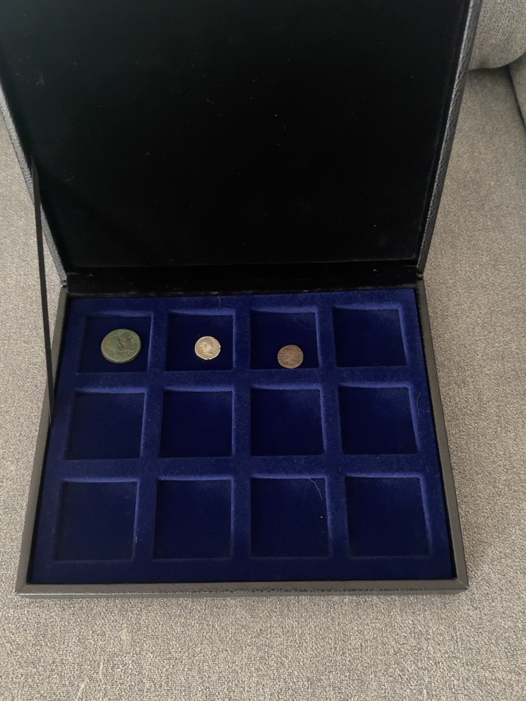 The collection’s open blue velvet case, photographed with its first three coins and room to grow